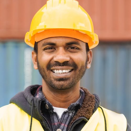 Happy Indian industrial worker man smiling at camera at shipping freight terminal port
